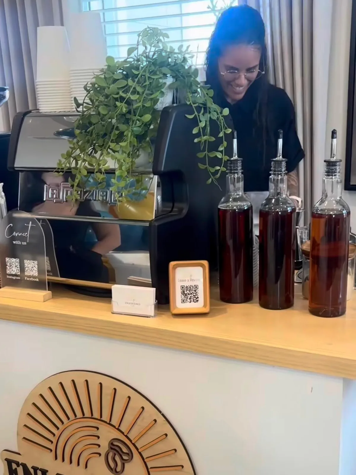Professional barista smiling behind the Enlightened Café coffee cart with house-made syrups