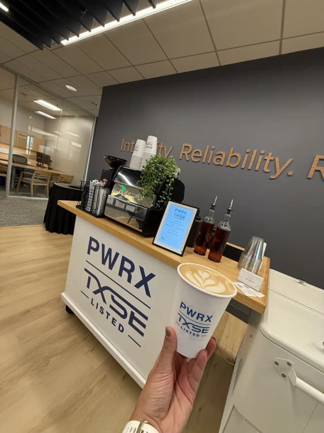Latte art in a PWRX-branded cup in front of the matching logo-branded Enlightened Café coffee cart at a corporate office event